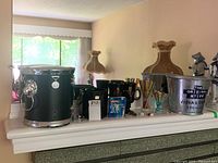 Photo showing two ice buckets, glass mugs, stir sticks, bottle opener arranged on a white mantle.