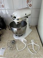 Photo showing KitchenAid Ultra Power mixer with the stainless steel bowl attached and three separate attachments placed in front on the counter: wire whisk, dough hook, and flat beater.