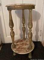 Full view of round occasional table showing top, shelf, and decorative metal legs