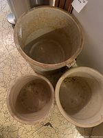Top down view of three empty stoneware pickling crocks showing glazed interior surfaces with some discoloration and wear