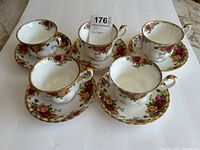Five Royal Albert Old Country Roses teacups with matching saucers arranged in a group showing top and side views, white background.