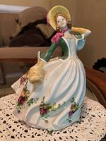 Front view of the Royal Albert porcelain figurine showing the woman in green and white dress with rose floral pattern, holding a basket, standing approximately 8 inches tall.