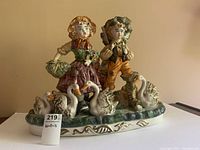 Front view of Capodimonte figurine showing girl and boy with six geese on ornamental base