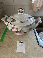 Photo showing the tureen from the front and side angle, displaying floral decorations, gold trim, and handles.