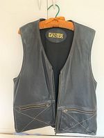 Front view of black leather vest showing zipper closure and two zippered pockets with skipped stitch detailing.