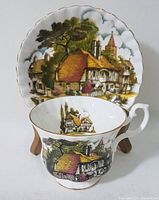 Teacup and saucer frontal angled view showing full village artwork and shape.