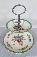 Front view of two-tier Royal Staffordshire serving dish showing floral patterns and metal handle.