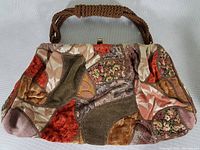 Front view of vintage handbag showing patchwork velvet and floral textured fabric sections with twisted rope handle.