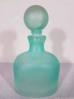 Front view of the entire bottle with round stopper showing frosted green opalescent glass and shape.