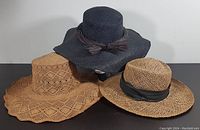 Three ladies sun hats displayed together on a black surface showing different designs and colors