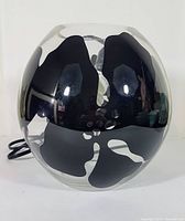Front view of the IKEA Knubbig round globe lamp showing the black floral hibiscus design on glossy glass surface.