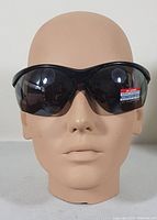 Front view of black Foster Grant IRONMAN TRIATHLON sunglasses on a mannequin head showing full frame and lens shape.