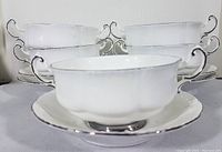 Set of five white bone china double handle soup bowls stacked with their matching saucers beneath them, showing platinum trim and handles