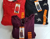 Three Buffalo David Bitton women's long sleeve tops folded with tags and size labels, colors and patterns visible.