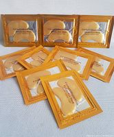 Set of 8 individually packaged Crystal Collagen Gold Powder Eye Masks arranged on a white surface.