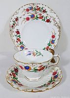 Four-piece luncheon set displayed showing the teacup on the saucer with the salad plate behind, highlighting the colorful hand-painted floral design and gold detailing on the edges.