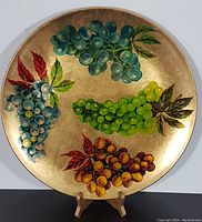 Full view of the vintage round serving tray with colorful grape clusters on a gold background.