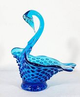Side view of turquoise hobnail glass swan showing curved neck, hobnail texture, and clear glass tip on beak.