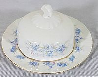 Butter dish with lid showing the top of the lid with floral decoration and gold trim on plate edge