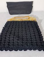 Full view of the handbag showing shell stitch pattern, carved handle, and matching change purse behind