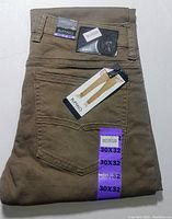 Folded tan denim jeans with visible Buffalo David Bitton and Sam-X branding tags and size labels (30x32).