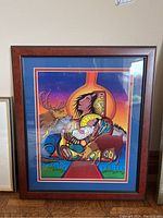 Full view of the framed and matted print showing Indigenous-style colorful animal design and wood-tone frame.