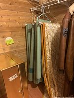 Photo showing wool blankets hanging on hangers alongside quilted bedspreads and part of a leather jacket.