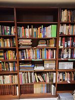 Full view of tall wood bookcase filled with books showing wood finish and shelf count.