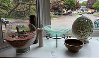 Wide view of the lot including glass terrarium, white vases, brown ceramic bowl, glass bowl on stand, and decorative lamp