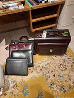 Overview showing all five briefcases and document holders including the brown carry-on sized briefcase and four slimmer black and dark brown cases.