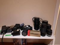 Overview of all items on shelf including camera body, lenses, winder, flashes and adapters