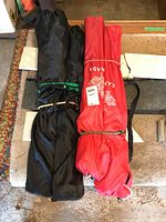 Two folded chairs in carrying bags, one black and one red, placed side by side.