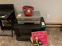Panasonic DVD and VHS player combo with red rotary dial telephone on top and LP leaning nearby.