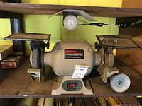 Front view of Shopcraft 6 inch heavy duty bench grinder showing dual grinding wheels, tool rests, and integrated light above.