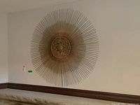 Full view of the large metal sunburst wall decor mounted on a white wall.