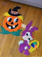 Two vintage 1970s plastic popcorn decorations on wooden floor: a Halloween jack-o-lantern with witch hat and an Easter bunny holding a basket.