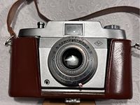 Front view of Agfa Silette Pronto camera showing lens and partial leather case covering.