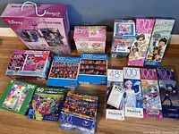 Photo showing a variety of children's jigsaw puzzles from Disney, Puzzlebug, LOL Surprise and others, arranged for clear product visibility.