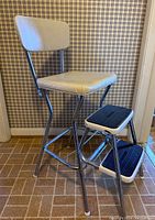 Side view showing padded white seat and backrest, chrome metal frame, and two rubber-treaded steps.