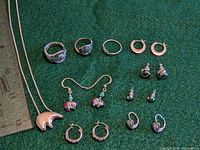 Photo showing sterling silver jewelry including bear pendant necklace, spoon rings, silver knot ring, and various silver earrings.