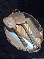 Photo showing the full vanity set laid out on the ornate metal tray, including hand mirror, hairbrush, and comb.