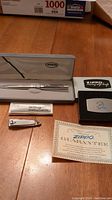 Zippo branded silver-tone pen in original cushioned case alongside vintage nail clipper, money clip cutter, and Zippo guarantee card.