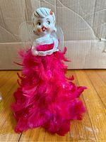 Front view of vintage angel tree topper with detailed facial features, pink feathered skirt, and white fabric wings.