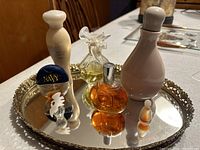 Top photo of all six collectible vintage perfume bottles arranged on the ornate mirrored tray, showing variety in shapes and colors