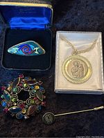 Weiss brooch, TaraWare pin, religious medal necklace and initials stick pin displayed together