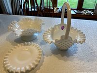 Photo showing three white hobnail art glass pieces on a table with natural light: a handled basket and two bowls