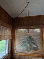 Full view of the white wicker swag hanging lamp suspended from chain in room corner.