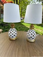 Full view of two pineapple table lamps side by side on a wooden surface outdoors