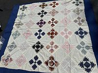 Full view of the handmade quilt top showing geometric patchwork patterns in various colors on a white background