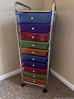 Front view of the rolling organizer cart showing the colorful drawers and metal frame with caster wheels.